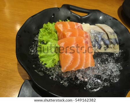 Photo of raw Salmon and Saba fish with vegetable and ice in plate on table