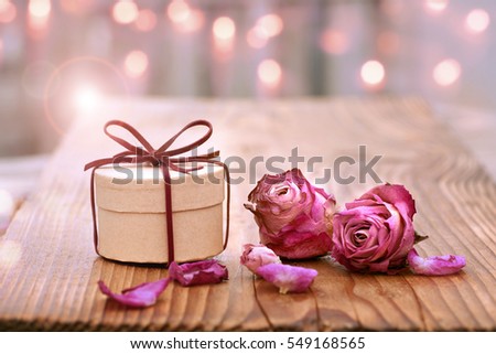 Romantic still life on wood with dried rose blossom and a gift for Mothers Day or Valentines Day