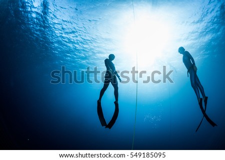 Two free divers, man and woman, ascending from the depth Royalty-Free Stock Photo #549185095