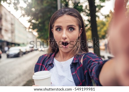 Gasping young woman talking a selfie in the city