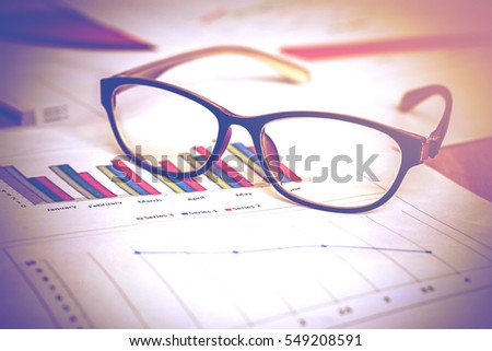 eyeglasses over report paper on table in working room vintage color tone,abstract background for business planer solution concept.