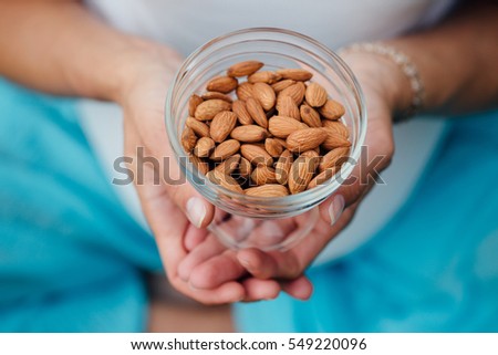 Close Up Of Woman Holding glass bowl with Almonds nuts. Healthy Organic Food. Royalty-Free Stock Photo #549220096