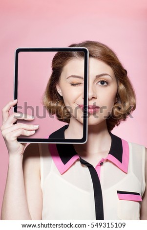 Woman covering half her face with digital tablet