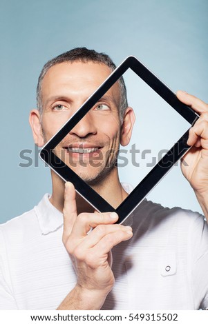 Man covering half his face with digital tablet