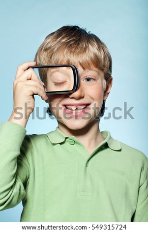 Boy holding smartphone over eye