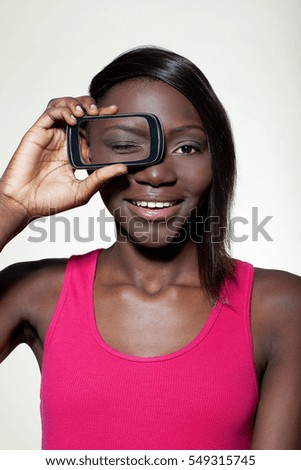 Teenage girl holding smartphone over eye