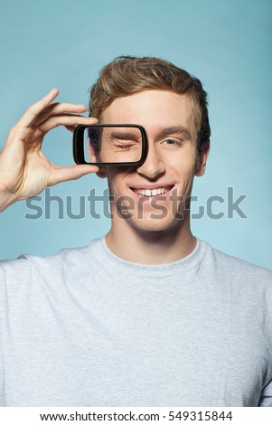 Man holding smartphone over eye