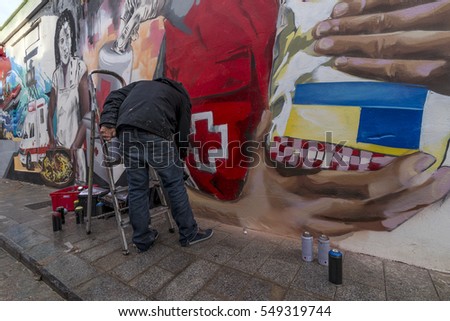 Street art artist paints graffiti inspired by the Red Cross on the streets of the historic center of Valencia, Spain