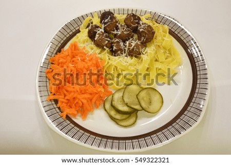 Meatballs and pasta with grated carrot, parmesan cheese and pickled cucumbers, picture from the Northern Sweden.