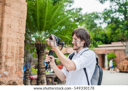 Man videographer shoots video in the electronic stabilizer, steadycam To shoot at Po Nagar Cham Tovers. Digital technology concept. Devices for shooting video concept. Asia Travel concept. Royalty-Free Stock Photo #549330178