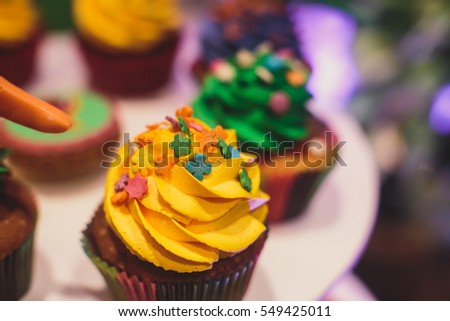 Beautiful multicolored decorated baked sweet tasty candy bar dessert on kids children party with happy people around, catering banquet table