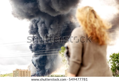 A dense and dark smoke from a fire, in the midst of a large population