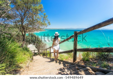 A woman looking back towards Wategoes beach at Byron Bay on Australia's east coast Royalty-Free Stock Photo #549489649