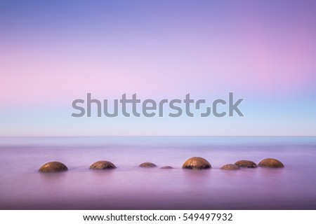 Moeraki Boulders in the ocean at dawn with beautiful pink and blue sky before sunrise Royalty-Free Stock Photo #549497932