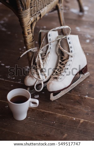 A pair of ice skates with cup of tea standing on the floor