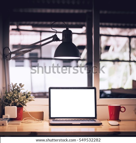 Laptop with blank screen on table in home studio, vintage tone Royalty-Free Stock Photo #549532282