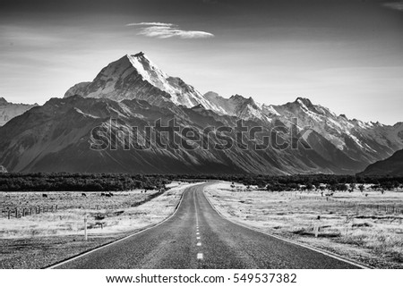 A road leading towards a large snow capped mountain in black and white Royalty-Free Stock Photo #549537382