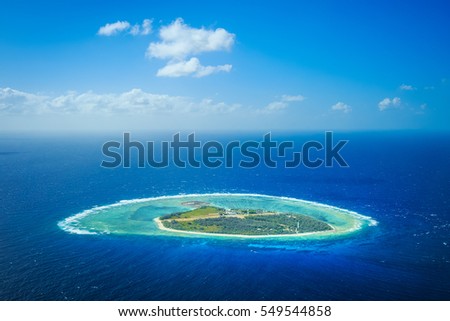A aerial of a coral cay island surrounded by shallow reef and deep blue water Royalty-Free Stock Photo #549544858
