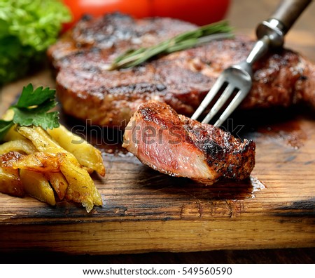 grilled juicy steak with rosemary.  Royalty-Free Stock Photo #549560590