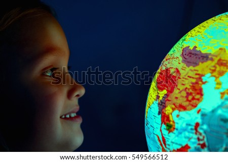 girl - a child of seven years, carried away by the geography  the study examines the world globe on  dark background similar to space
