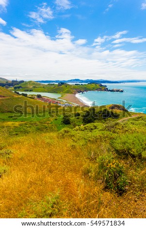 San Francisco in distant background seen from atop the Marin Headlands above Fort Cronkhite and Rodeo Beach along nature of the coastal trail on a summer day in California. Vertical Royalty-Free Stock Photo #549571834