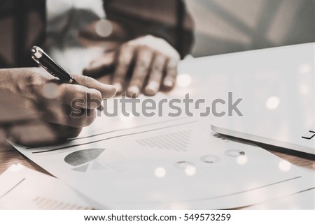 Close up of people working with graph and laptop on his wooden table in the office on business concept