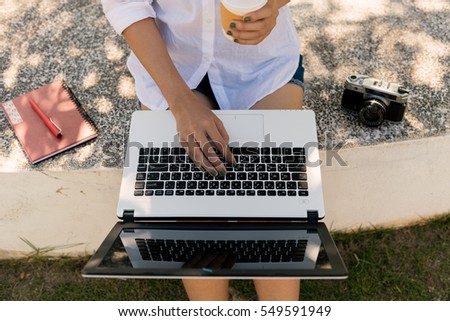 Relaxation with a cup of coffee and tablet.Girl with laptop an coffee. Beautiful young woman green nail polish with notebook sitting on the park.