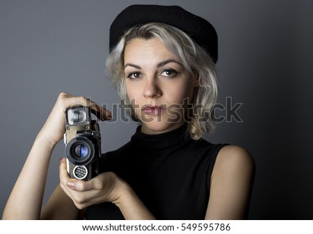 Woman holding a vintage video camera posing as a director, filmmaker, or cinematographer in the hollywood movie industry.  The image depicts creative arts.
