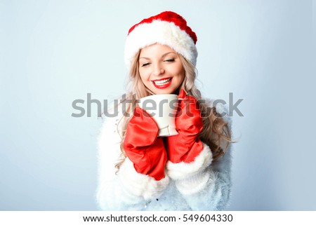 Young woman in Santa Claus cap with white coffe cup
