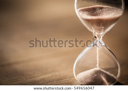 Hourglass as time passing concept for business deadline, urgency and running out of time. Royalty-Free Stock Photo #549656047
