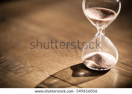 Hourglass as time passing concept for business deadline, urgency and running out of time. Royalty-Free Stock Photo #549656056