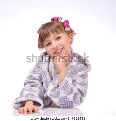Little nice girl with curlers on her head. Photo on a white background.