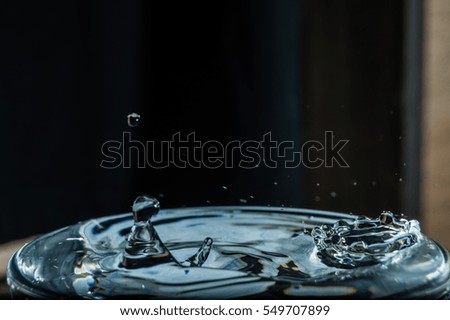 a drop of water hits the surface of the water splash on the water crown on the surface of the liquid abstract concept close-up stopped motion freezing