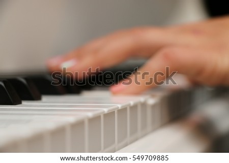 The girl plays piano,close up piano, white and black keyboard