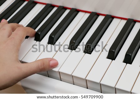 The girl plays piano,close up piano, white and black keyboard