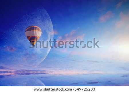 Amazing heavenly picture - colorful hot air balloon in blue sunset sky with rising full moon. Dream come true concept. Elements of this image furnished by NASA