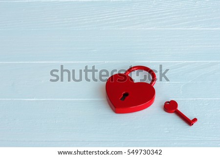 Heart shaped red padlock with key on white wooden background