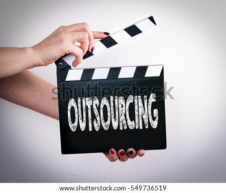 Outsourcing. Female hands holding movie clapper