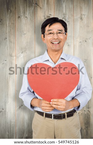 Older asian man showing heart against bleached wooden planks background