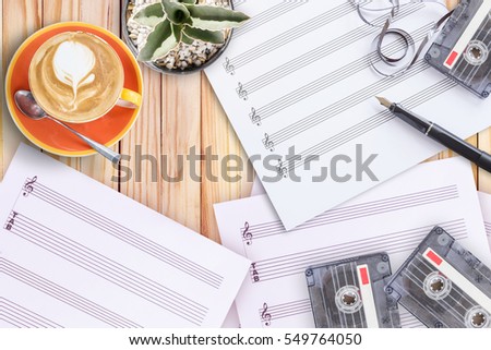 Top of view music concept set sheet music, cactus, fountain pen, tape cassette and coffee latte on wooden table, creation concept idea with copy space for text