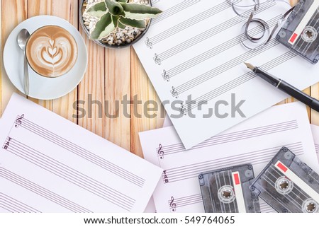 Top of view music concept set sheet music, cactus, fountain pen, tape cassette and coffee latte on wooden table, creation concept idea with copy space for text