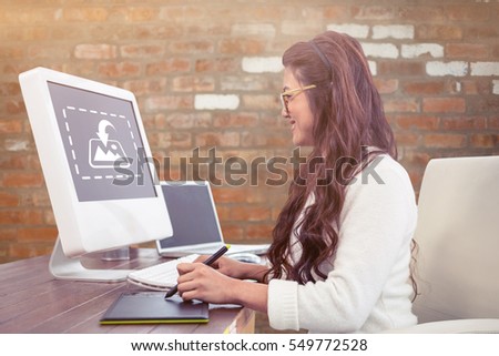 Smiling Asian woman using digital board and computer against brick wall