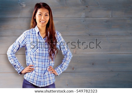 Smiling asian woman with hands on hips against bleached wooden planks background
