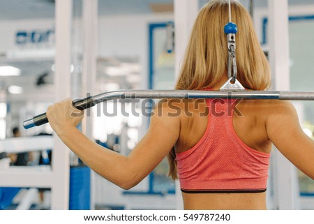 Close up photo of young girl working out on a fitness station in gym