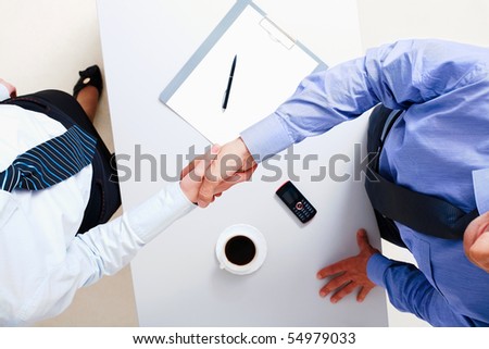 Above view of businessman and businesswoman shaking hands over table
