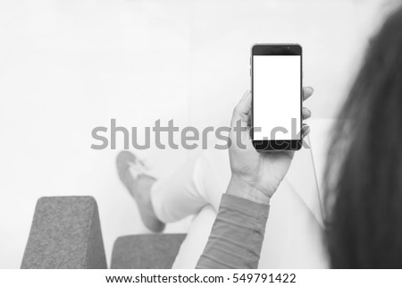 Woman hand holding contemporary modern smartphone. Monochromatic.Black and white. Blank display replaceable with needed design.Mockup