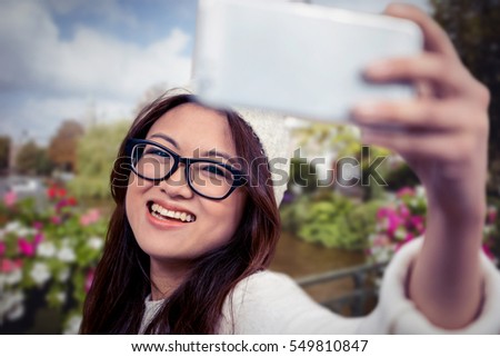 Smiling Asian woman taking selfie against canal in amsterdam