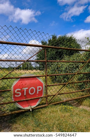 Makeshift stop sign seen at the entrance to a field in a rural location.