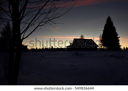Winter sunset in the mountains. Silhouette of a lodge