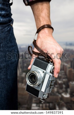 Hipster man holding digital camera against new york